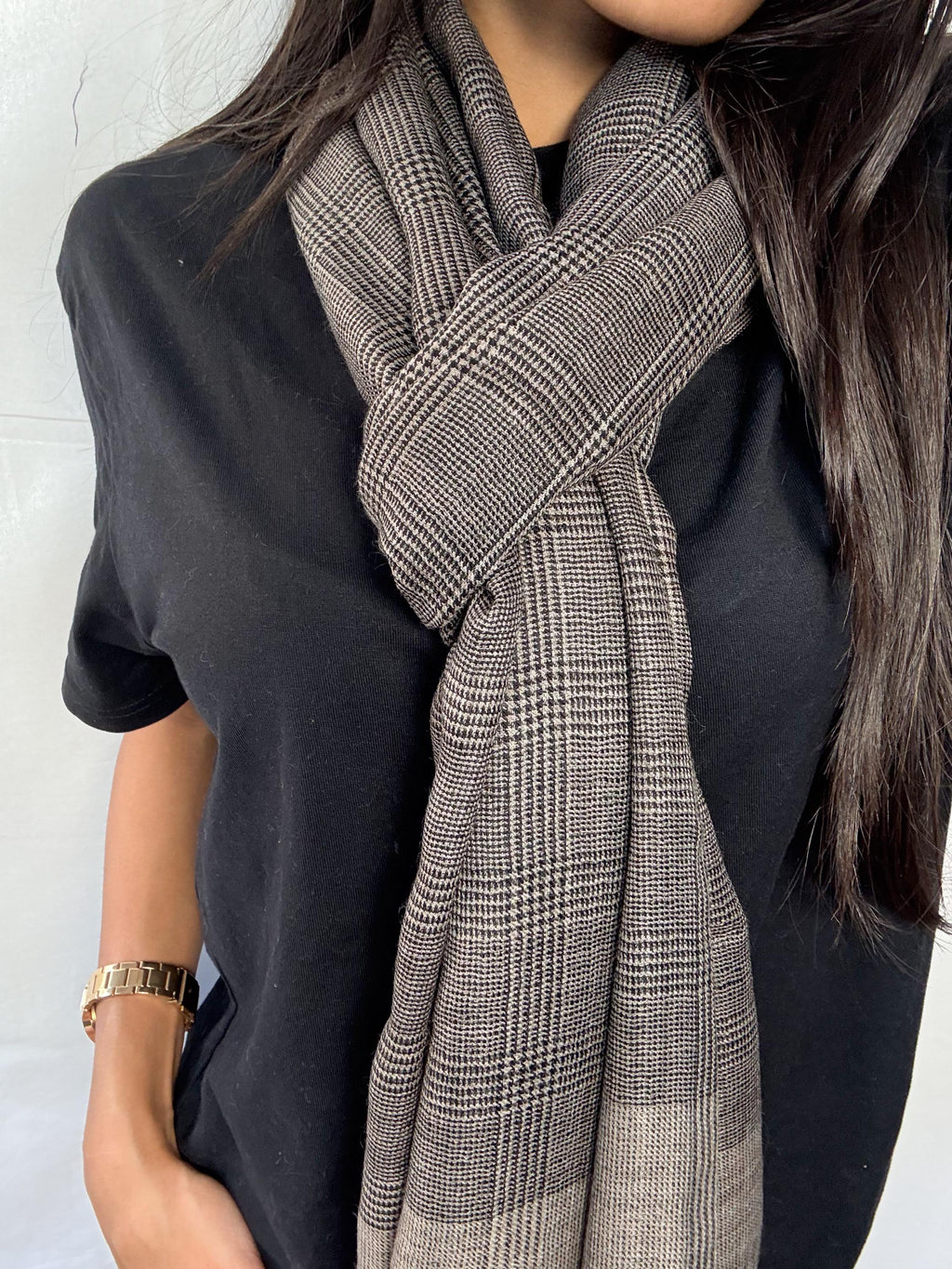 Person wearing a black shirt and plaid scarf against a white background