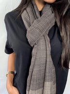 Person wearing a black shirt and plaid scarf against a white background