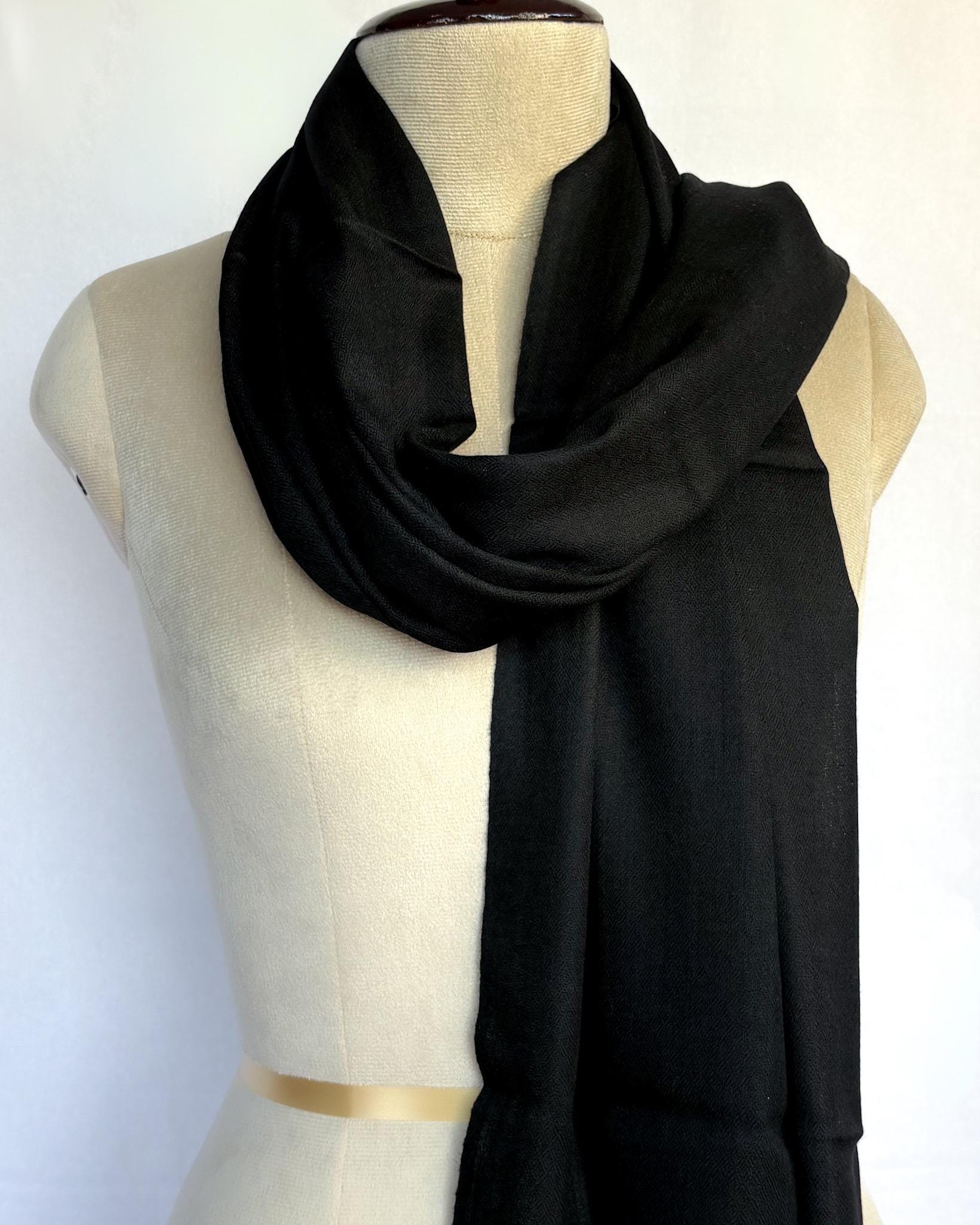 Black scarf draped over a mannequin on a white background