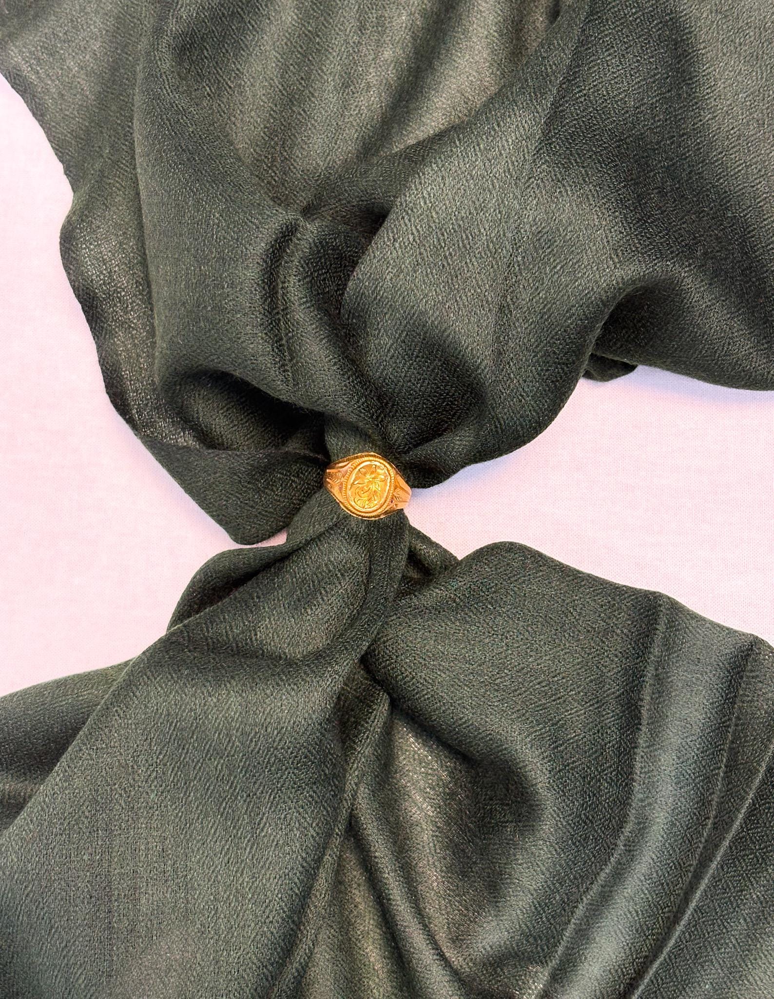 Green fabric with a gold button on a light pink background
