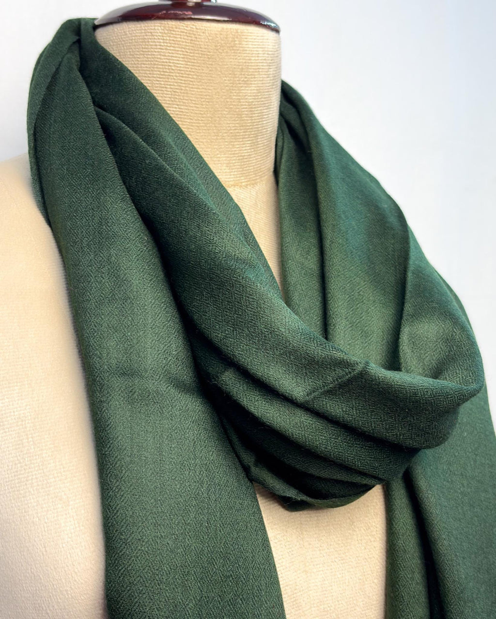 Green scarf draped over a mannequin on a white background